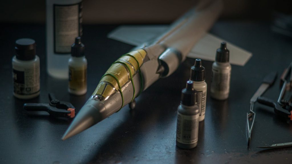 Close-up of a scale model F-104 Starfighter with modeling tools and paints on a desk.