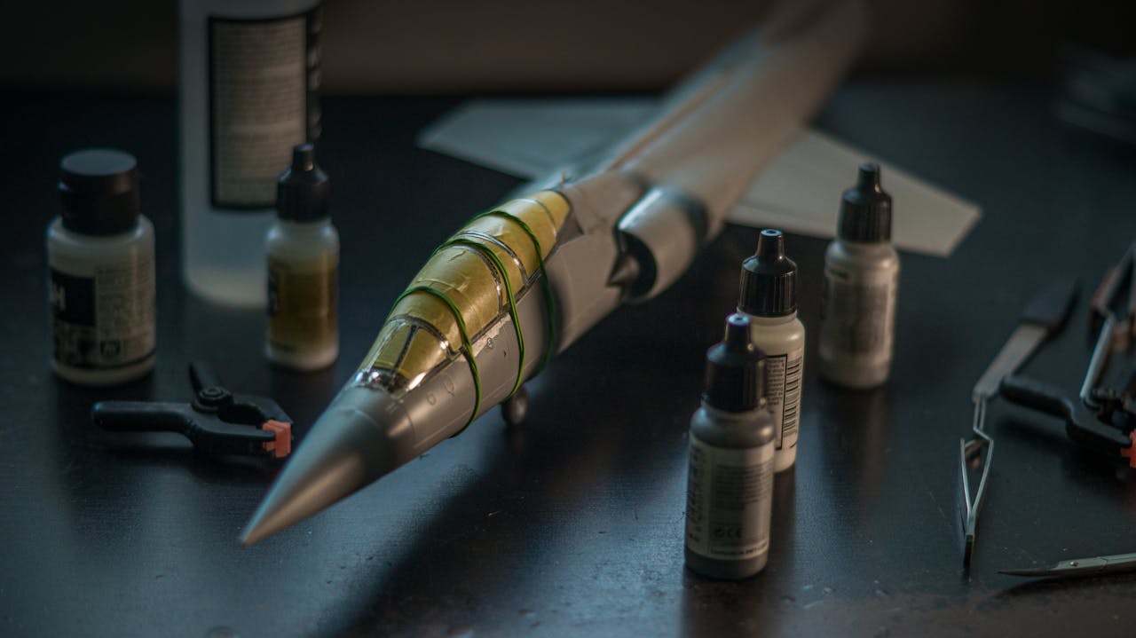 about-bg Close-up of a scale model F-104 Starfighter with modeling tools and paints on a desk.