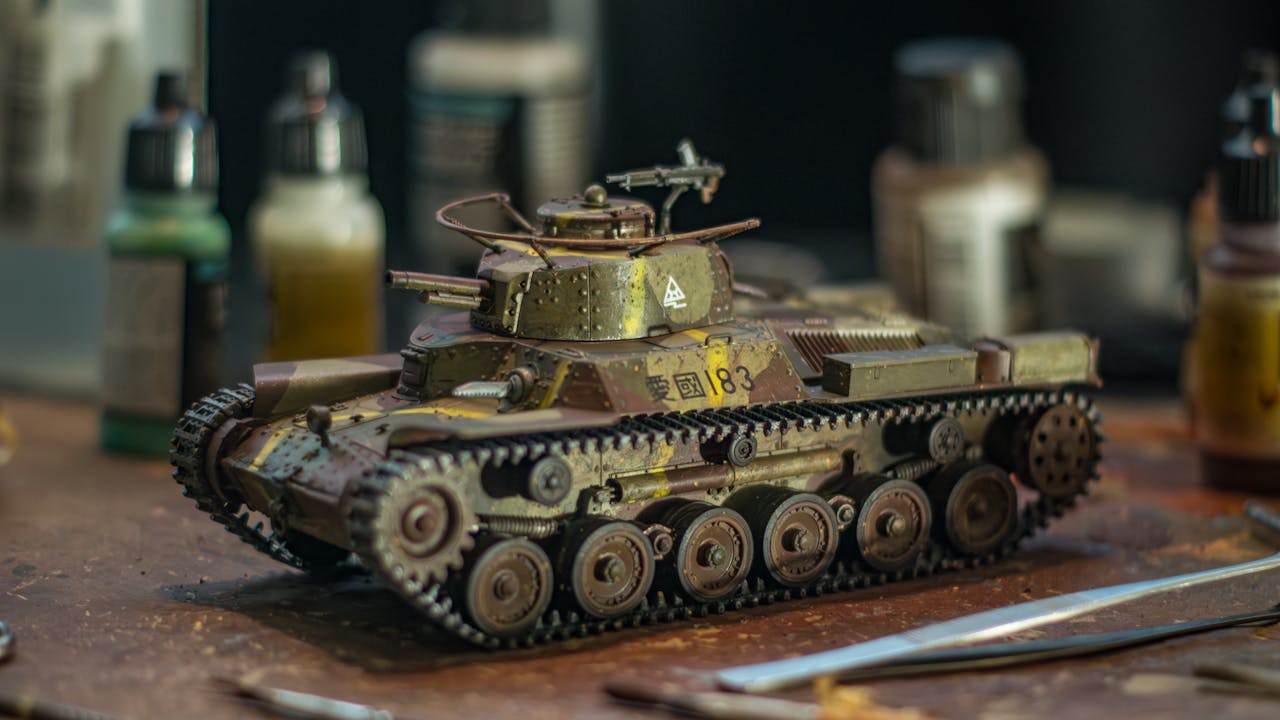 Close-up of a detailed model tank on a crafting workspace with paint bottles in the background.